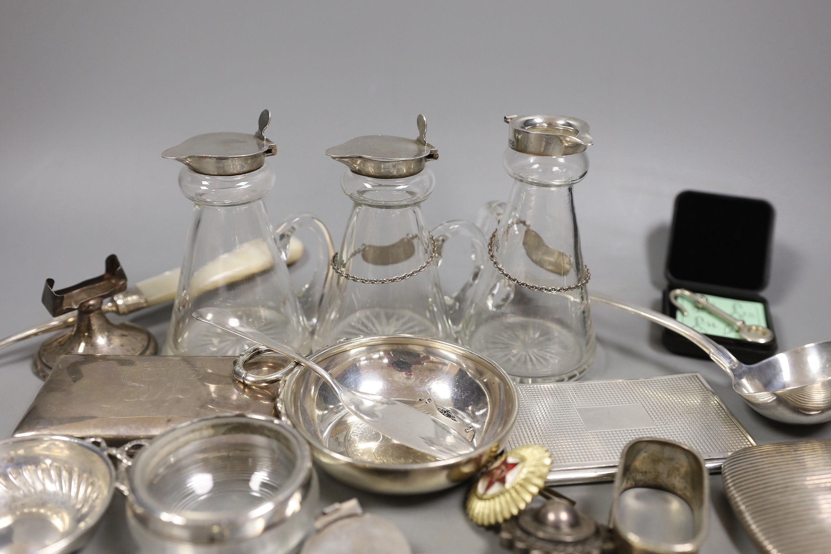 A silver mounted cigar cutter, a similar sterling mounted cutter and a collection of small silver and white metal items including three silver mounted whisky tot jugs including a pair by Asprey & Co, Birmingham, 1913, cu